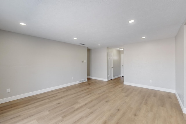 unfurnished room with a textured ceiling and light wood-type flooring