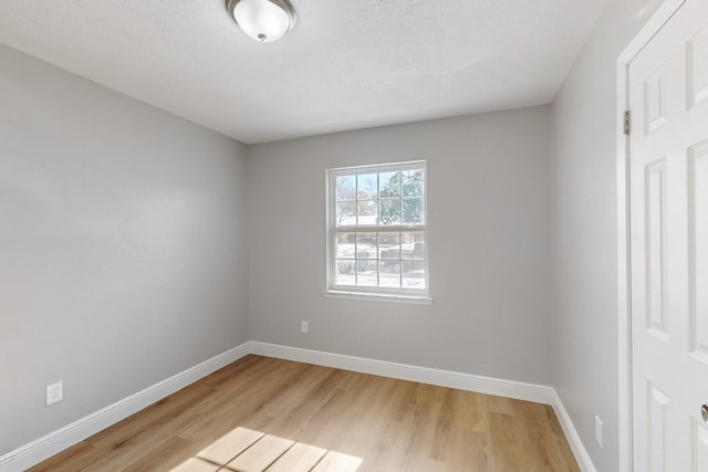 spare room featuring light hardwood / wood-style flooring and a textured ceiling