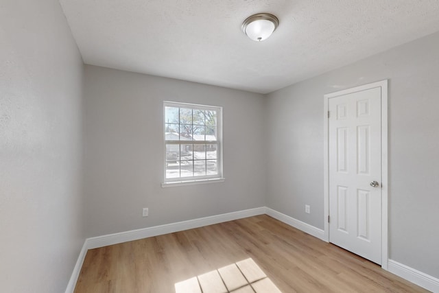 empty room with light hardwood / wood-style floors and a textured ceiling