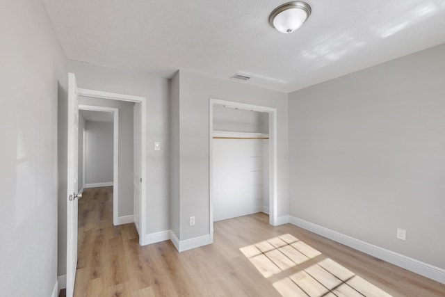 unfurnished bedroom featuring light hardwood / wood-style floors, a textured ceiling, and a closet