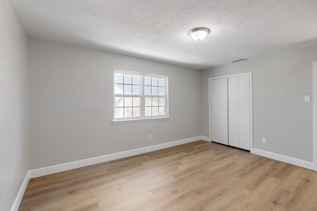 unfurnished bedroom featuring a closet, a textured ceiling, and light wood-type flooring