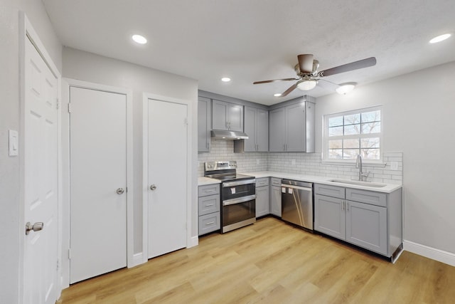 kitchen featuring backsplash, light hardwood / wood-style floors, stainless steel appliances, sink, and gray cabinets