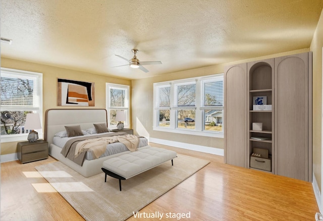 bedroom with ceiling fan, a textured ceiling, and light wood-type flooring