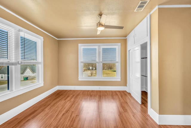 interior space featuring crown molding, a textured ceiling, and light hardwood / wood-style flooring