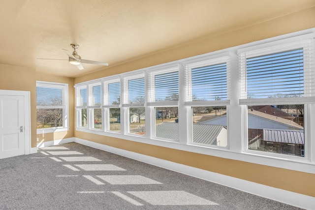 unfurnished sunroom with ceiling fan