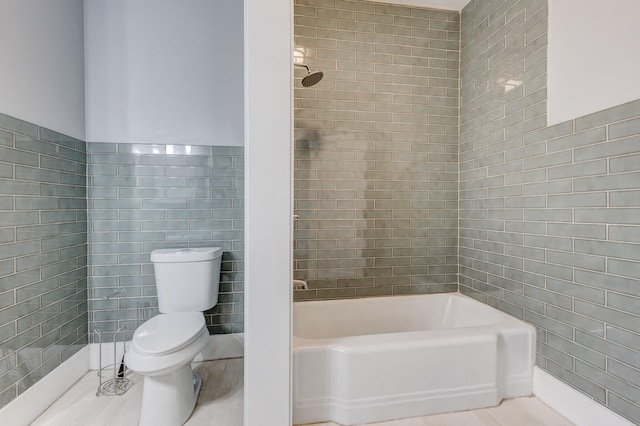 bathroom featuring tile walls, tiled shower / bath, tile patterned floors, and toilet