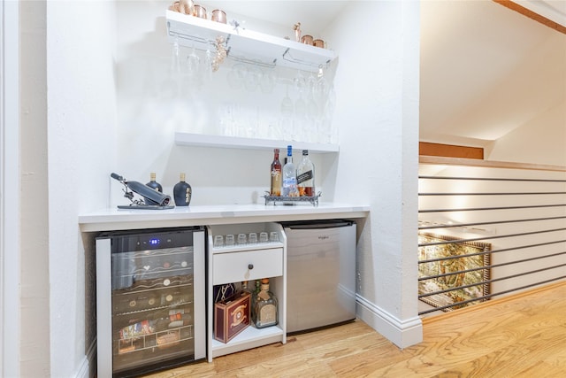 bar featuring hardwood / wood-style flooring, beverage cooler, refrigerator, and dishwashing machine