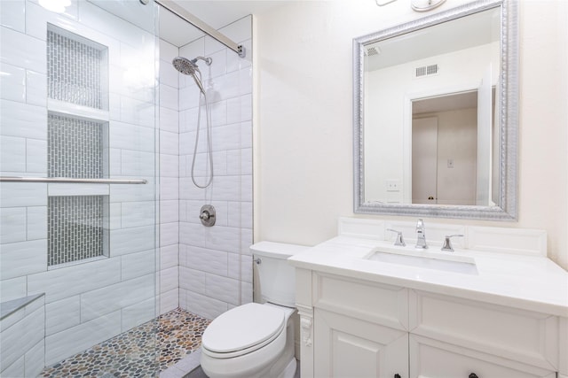 bathroom featuring a tile shower, vanity, and toilet