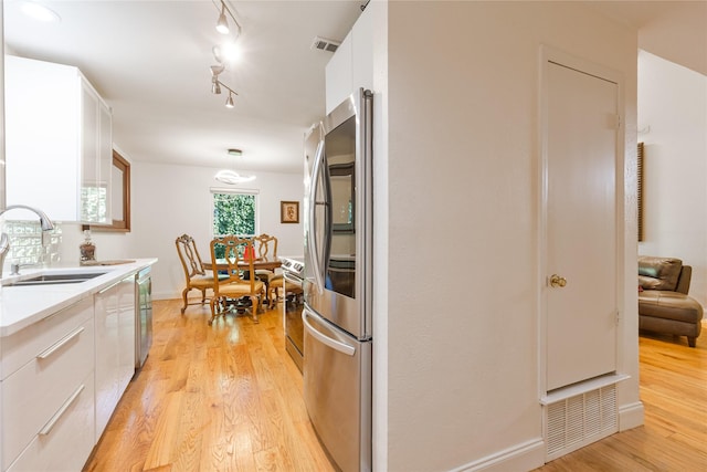 kitchen featuring white cabinets, appliances with stainless steel finishes, light hardwood / wood-style floors, and sink