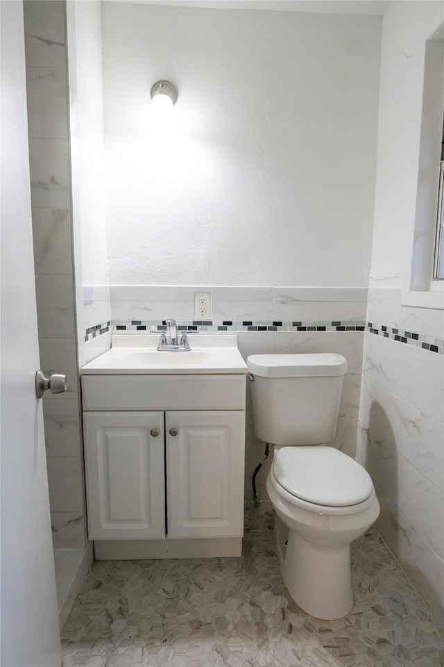 bathroom with tile patterned flooring, vanity, toilet, and tile walls