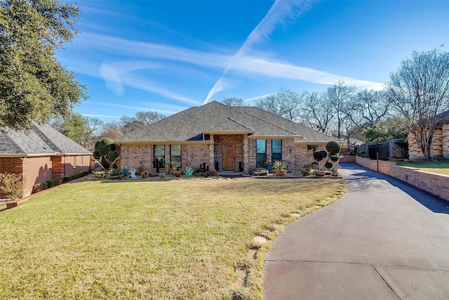 view of front of property with driveway, a front lawn, a shingled roof, and brick siding