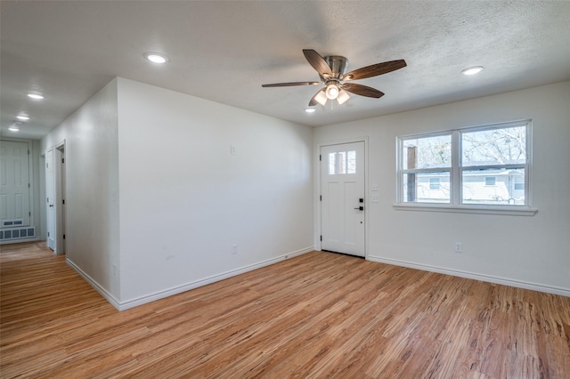 foyer with a textured ceiling, recessed lighting, light wood-type flooring, and baseboards