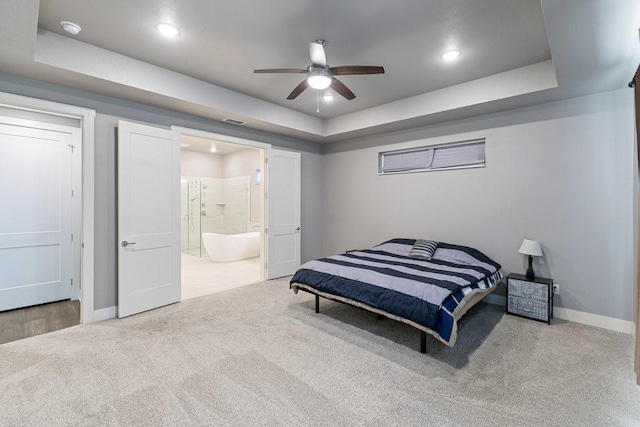 carpeted bedroom featuring ceiling fan, ensuite bathroom, and a raised ceiling