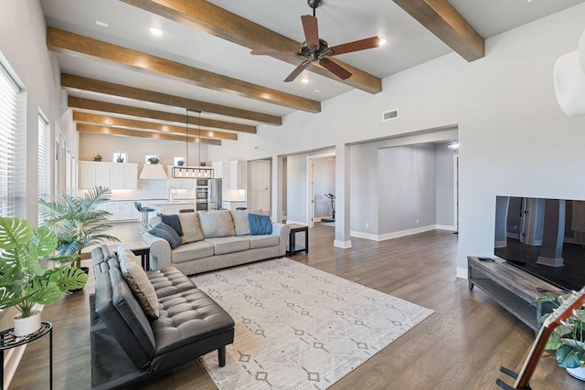 living room featuring ceiling fan, beam ceiling, and hardwood / wood-style floors