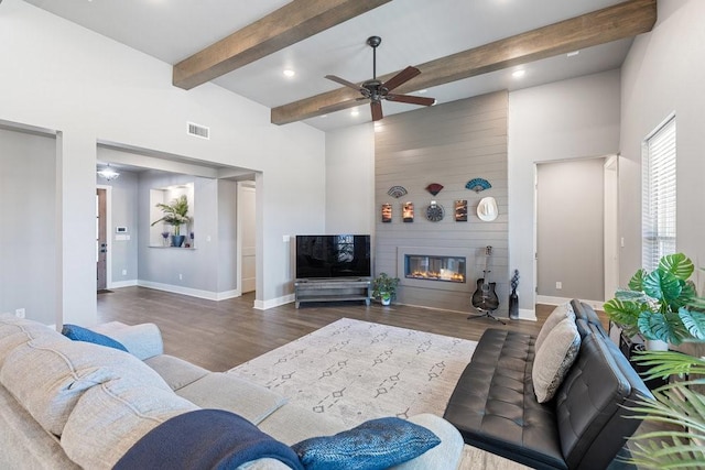 living room with ceiling fan, dark hardwood / wood-style flooring, beam ceiling, and a fireplace