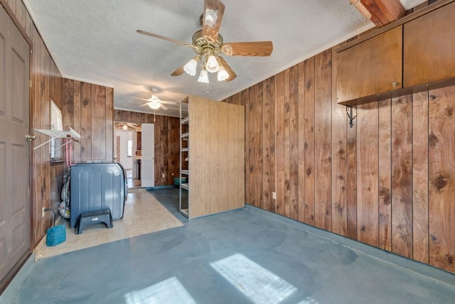 interior space featuring a textured ceiling, ceiling fan, and wood walls