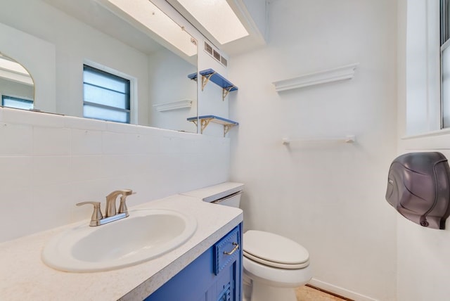 bathroom featuring vanity, toilet, and backsplash