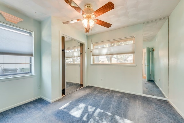 unfurnished bedroom with multiple windows, ceiling fan, a closet, and dark colored carpet