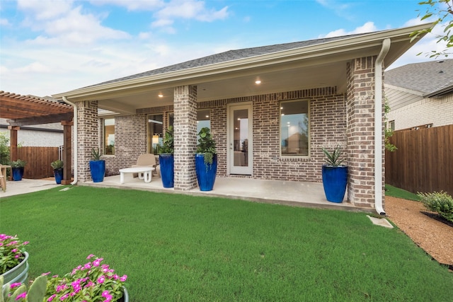 back of property with a pergola, a lawn, and a patio