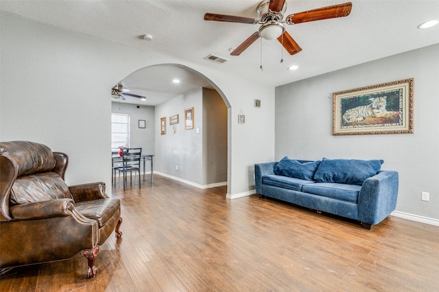 living room featuring ceiling fan, a textured ceiling, and light hardwood / wood-style flooring