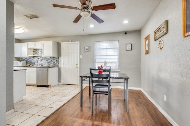 tiled dining room with ceiling fan and sink