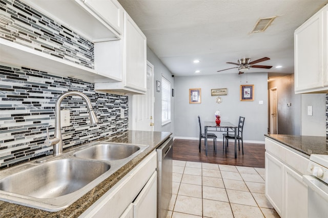 kitchen featuring white cabinets, light tile patterned floors, dark stone countertops, and sink