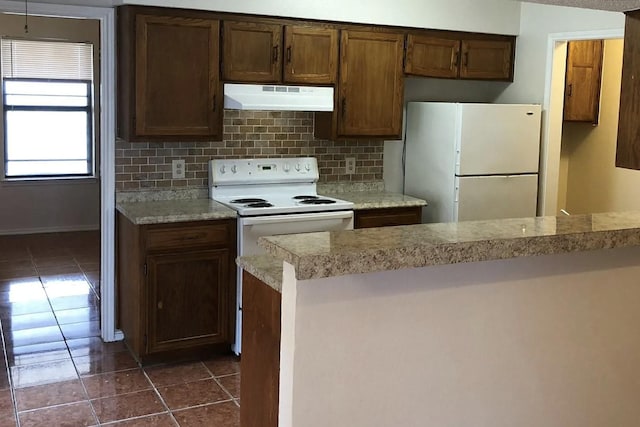 kitchen with white appliances, tasteful backsplash, and dark tile patterned floors