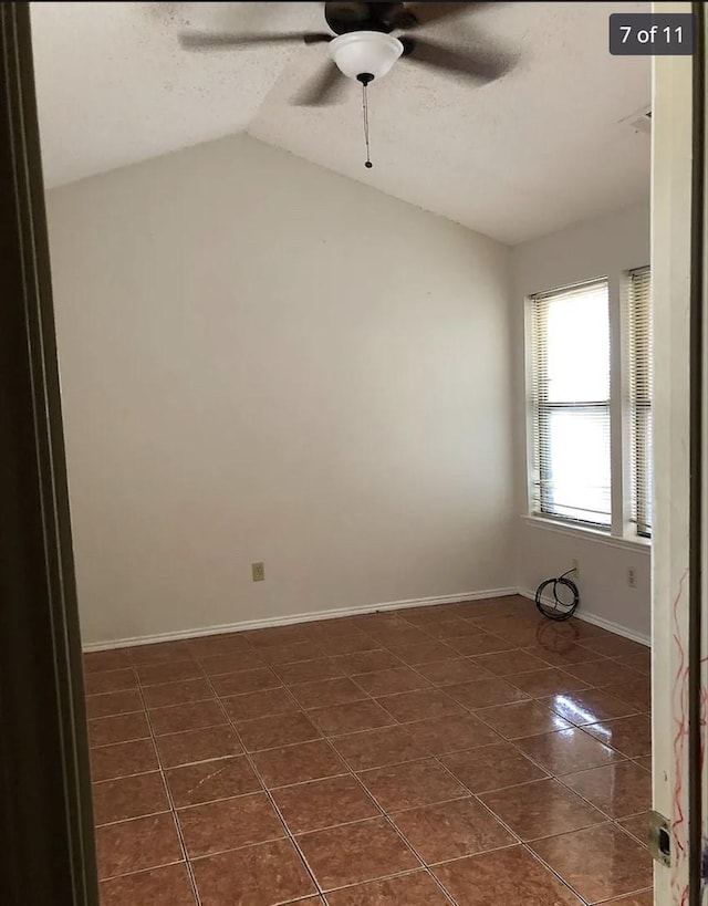 spare room featuring dark tile patterned flooring, ceiling fan, lofted ceiling, and a textured ceiling