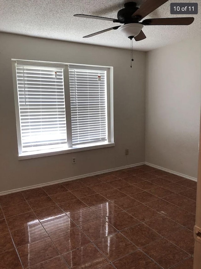 unfurnished room featuring dark tile patterned floors and ceiling fan