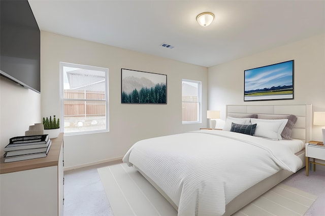 bedroom featuring light colored carpet and multiple windows