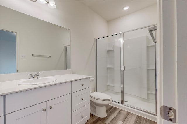 bathroom with wood-type flooring, vanity, toilet, and walk in shower