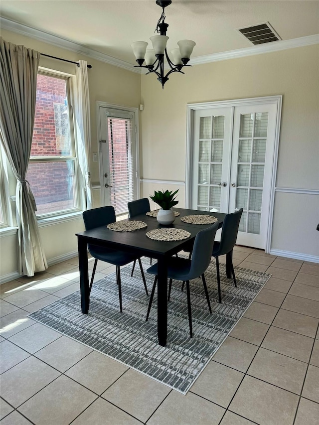 dining space with french doors, light tile patterned floors, ornamental molding, and an inviting chandelier