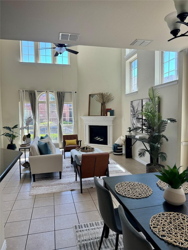 living room featuring ceiling fan, light tile patterned floors, and a towering ceiling