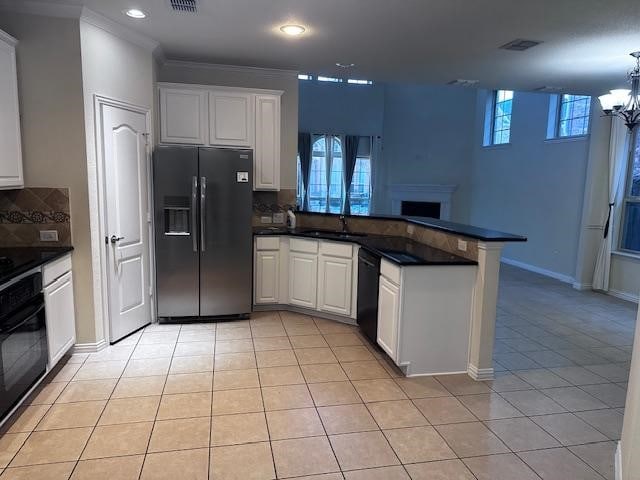 kitchen featuring tasteful backsplash, kitchen peninsula, white cabinets, and black appliances