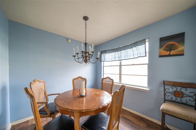 dining area featuring dark wood-type flooring, a textured ceiling, and a notable chandelier