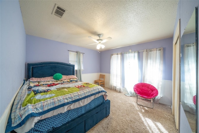 bedroom with carpet flooring, a textured ceiling, multiple windows, and ceiling fan