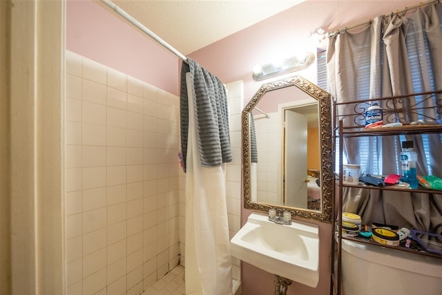 bathroom with curtained shower, sink, a textured ceiling, and toilet