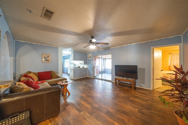 living room with a textured ceiling, dark hardwood / wood-style flooring, and ceiling fan