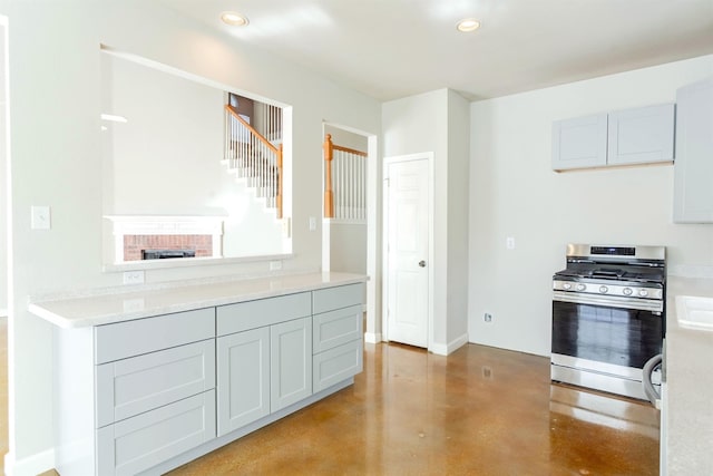 kitchen with light stone countertops, stainless steel range with gas cooktop, and a fireplace