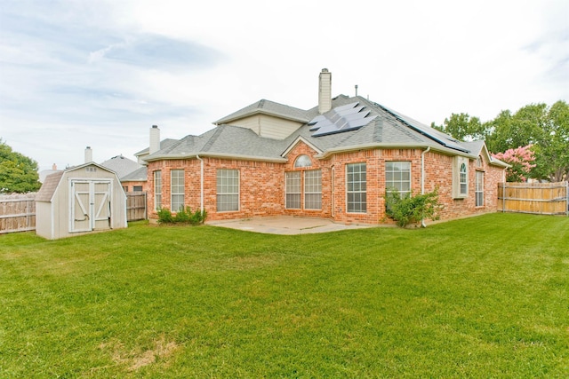 rear view of house with solar panels, a storage unit, a patio area, and a lawn