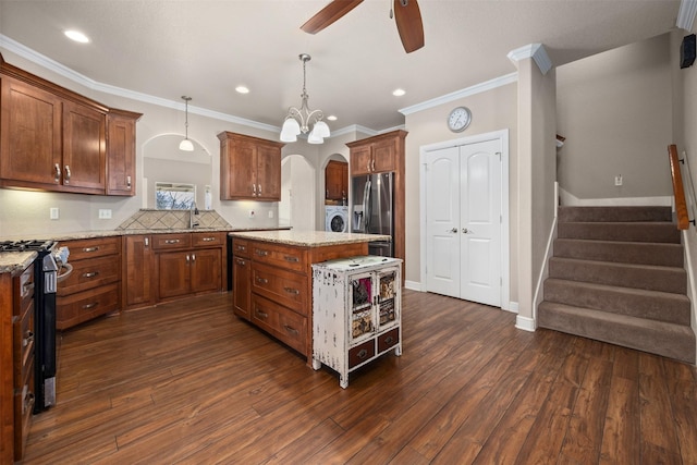 kitchen with a center island, hanging light fixtures, washer and dryer, light stone countertops, and appliances with stainless steel finishes