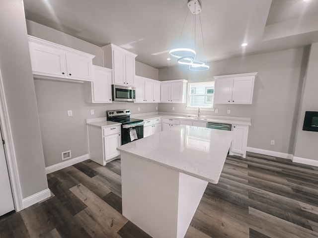 kitchen with white cabinets, appliances with stainless steel finishes, a center island, and hanging light fixtures