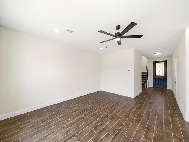 unfurnished room with visible vents, baseboards, stairs, a ceiling fan, and dark wood finished floors