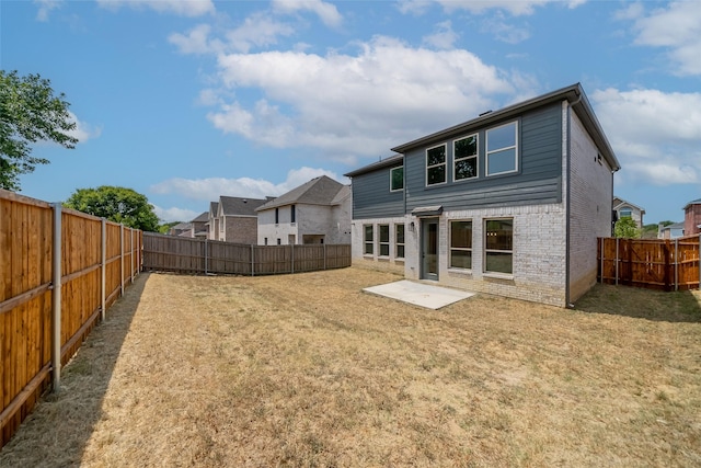 rear view of property featuring brick siding, a yard, and a fenced backyard