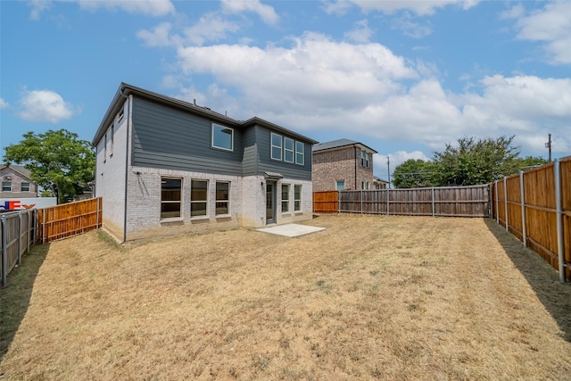 back of property with brick siding, a lawn, and a fenced backyard