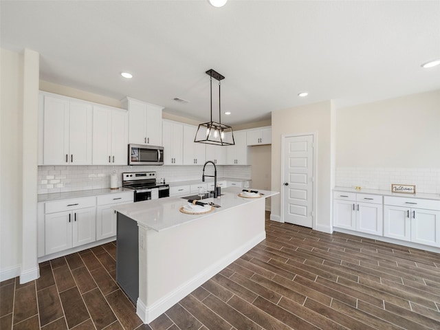 kitchen with stainless steel appliances, wood finish floors, white cabinetry, and a sink