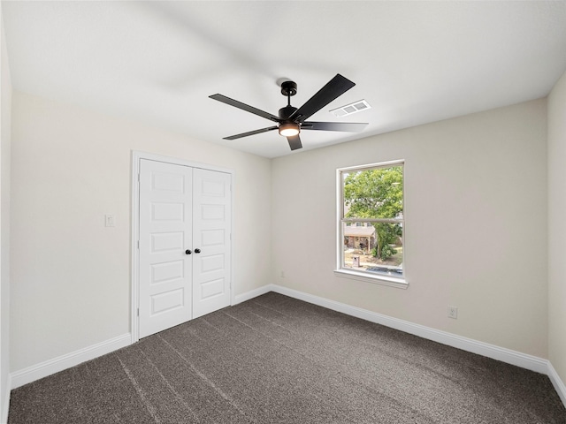 unfurnished bedroom featuring baseboards, visible vents, dark carpet, and a closet