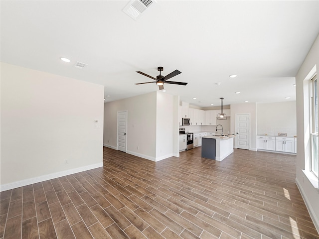 unfurnished living room with sink, hardwood / wood-style floors, and ceiling fan