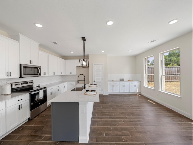 kitchen featuring tasteful backsplash, visible vents, appliances with stainless steel finishes, a sink, and an island with sink