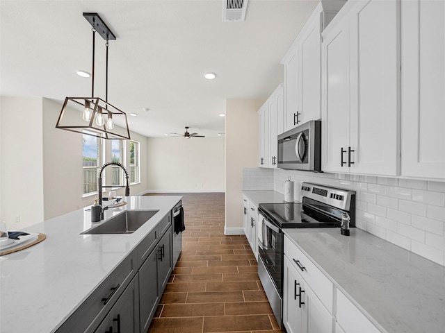 kitchen featuring stainless steel appliances, tasteful backsplash, visible vents, white cabinetry, and a sink